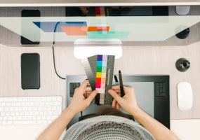 graphic-retoucher-choosing-colour-samples-from-patches-front-screen-with-digital-pen-hand-wearing-cap-glasses (1)