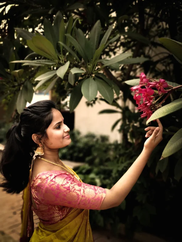 side-view-smiling-woman-wearing-sari-touching-flowers-plant